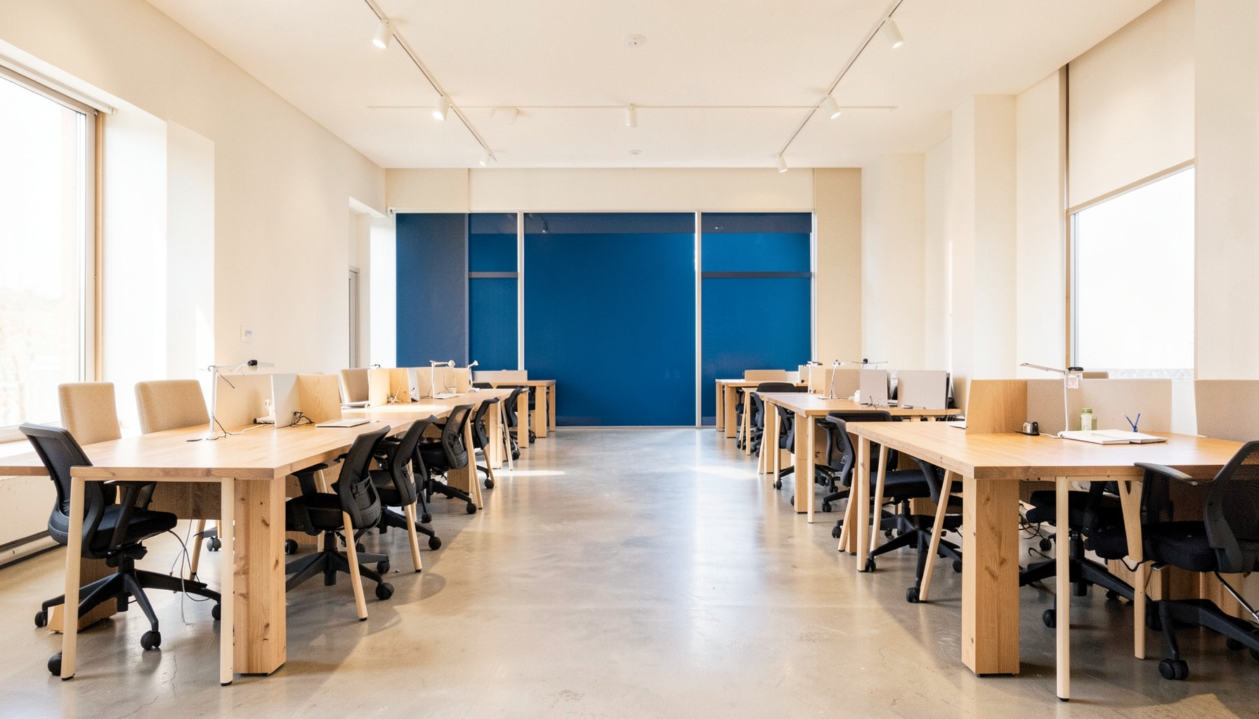 Bright, airy coworking space with natural light, wooden desks, and a calm, focused atmosphere in warm neutral tones