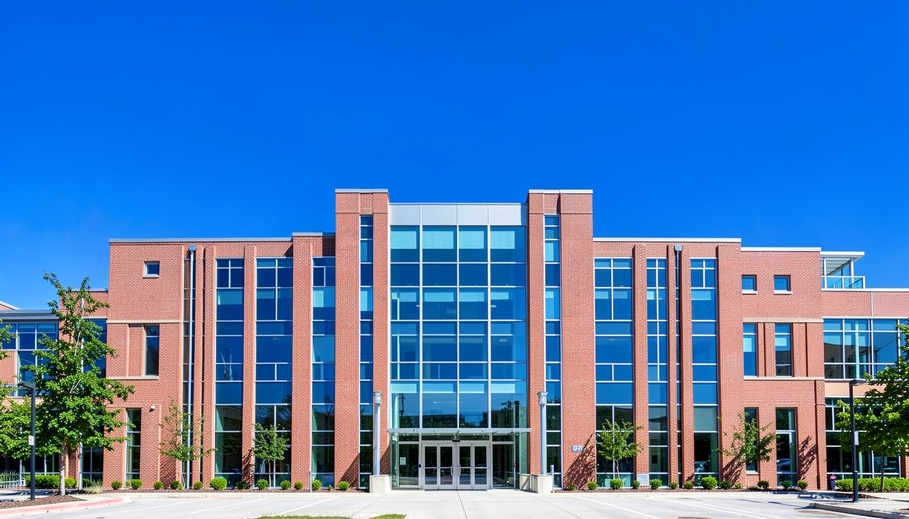 A bright, modern university campus building with clean brick and glass architecture, set against a clear blue sky, conveying academic energy and opportunity.