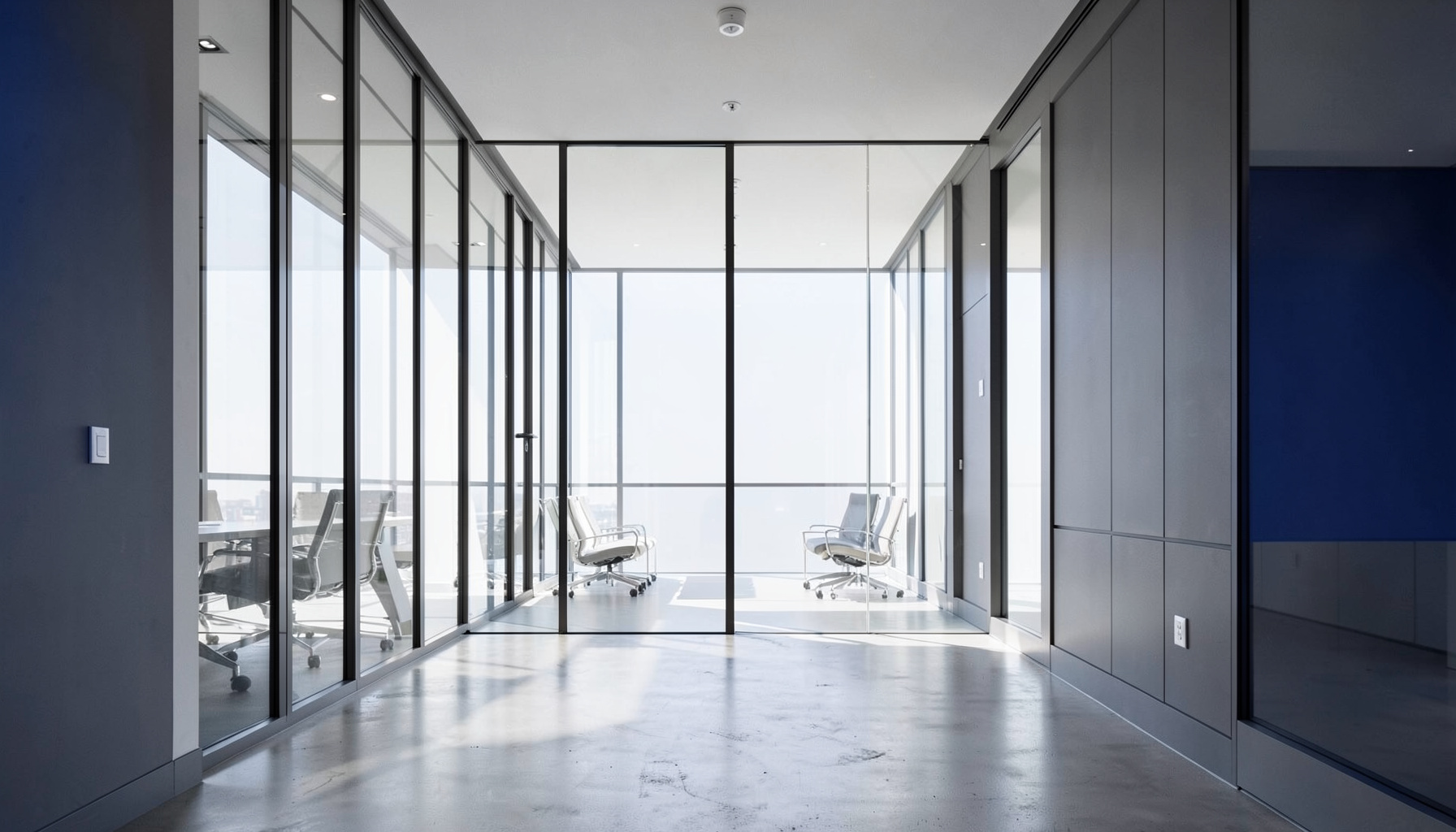 Clean architectural photograph of a modern glass-walled conference room with strong symmetry, natural daylight streaming through floor-to-ceiling windows, neutral gray and white tones